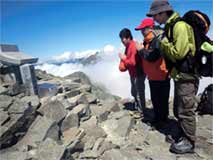 日本の山岳は古から宗教の霊山でもある。
苦労した登山者たちはごく自然に祠に手を合わせる。
遠景には槍ヶ岳がそびえる。
(撮影:穂高健一、9月5日、岐阜県・奥穂高山頂)